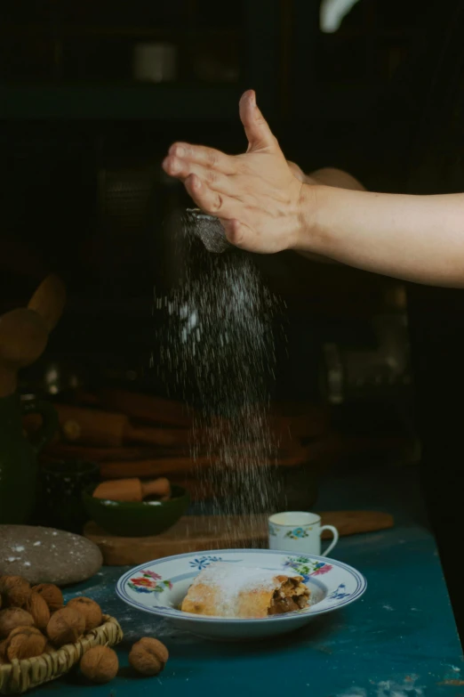 a woman sprinkling food on a plate with an empty cup