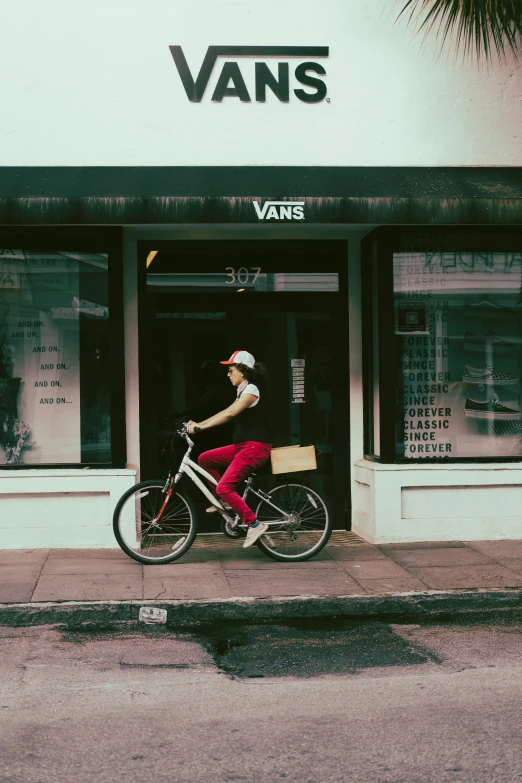 a person wearing a red pants rides a bike near a store