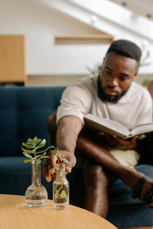 a man reads a book as he sits on a couch