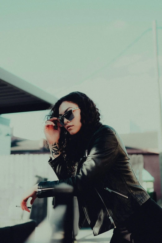 a person wearing sunglasses sits on a rail