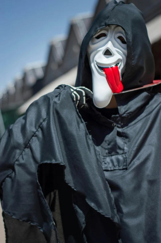 a person wearing a scary mask, a coat, and a tongue sticking out