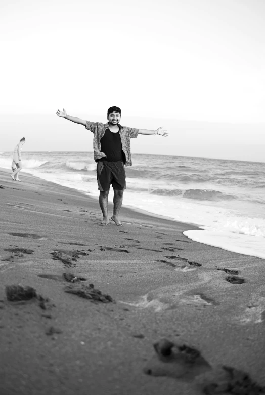 a man walking on a beach with one arm outstretched