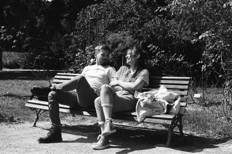 a couple sits on a park bench in front of trees