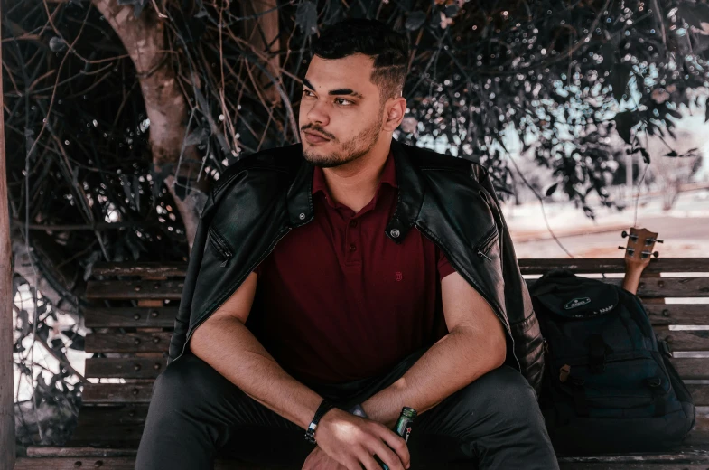 a man sitting on top of a bench next to a bag