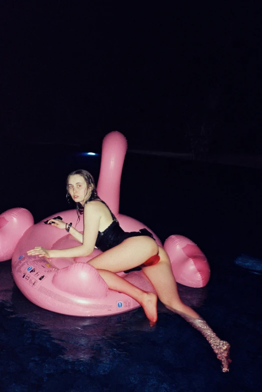 a woman in a black bikini is floating on an inflatable flamingo