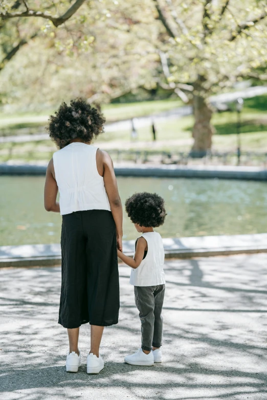 a mom holding her child's hand, with a tree in the background