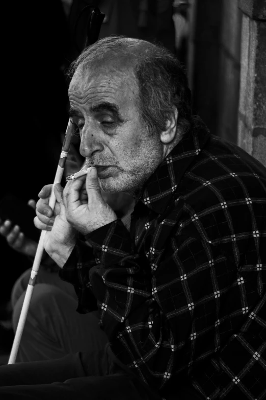 a man smokes a cigarette while holding a cane