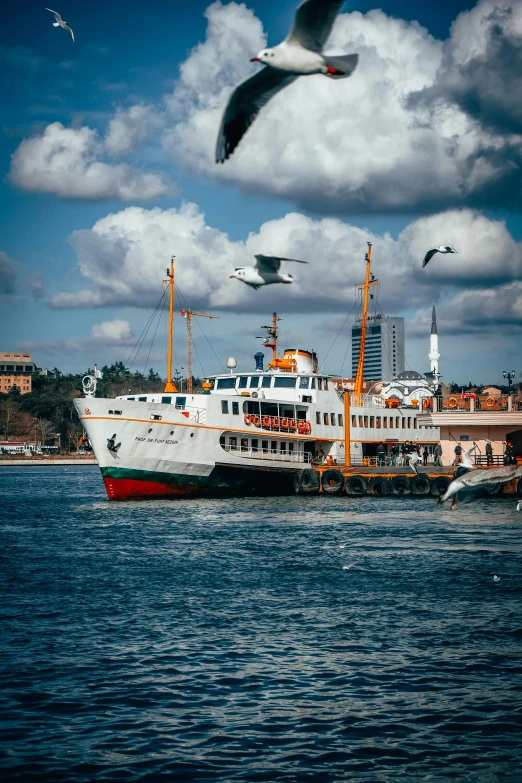 two seagulls are flying over the ocean while a large ship is in the water