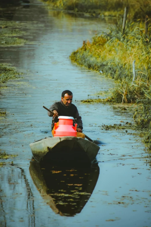 man paddles down a river in his canoe