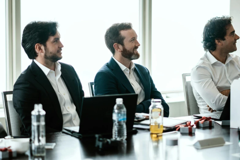 a group of men sit around a conference table