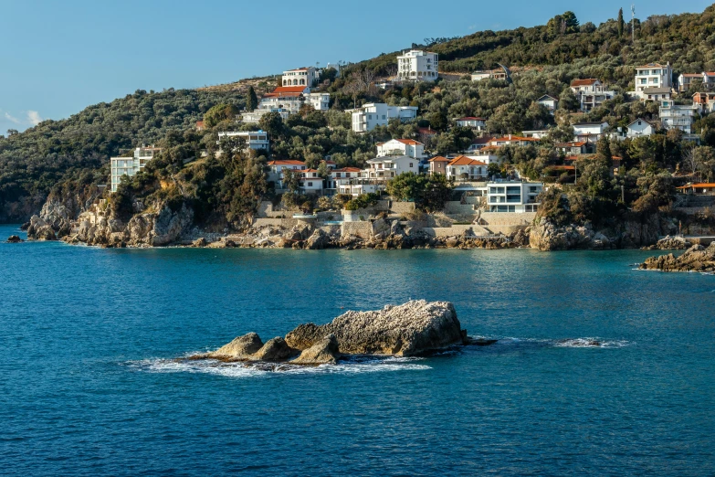 a large rock sits out on the ocean in front of a large town