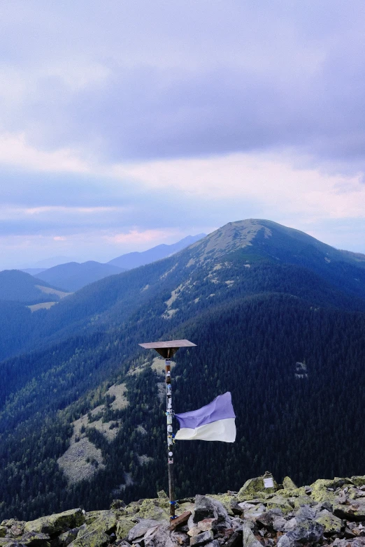 a mountain has mountains, trees and a sky in the distance