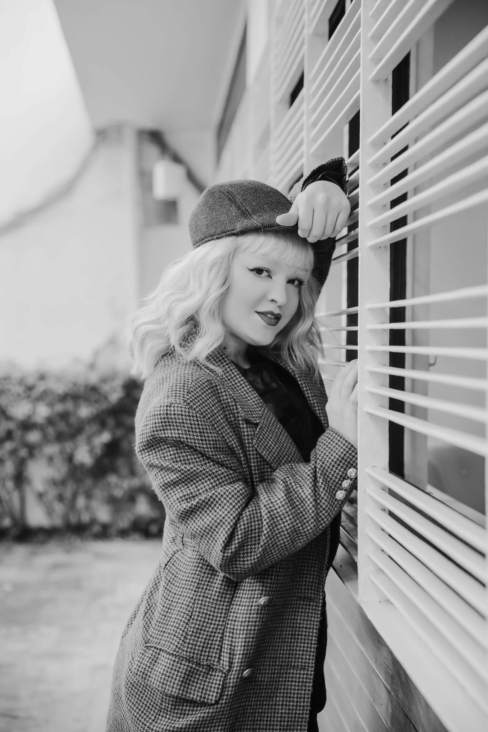 a blonde woman holding a handbag while leaning against the wall