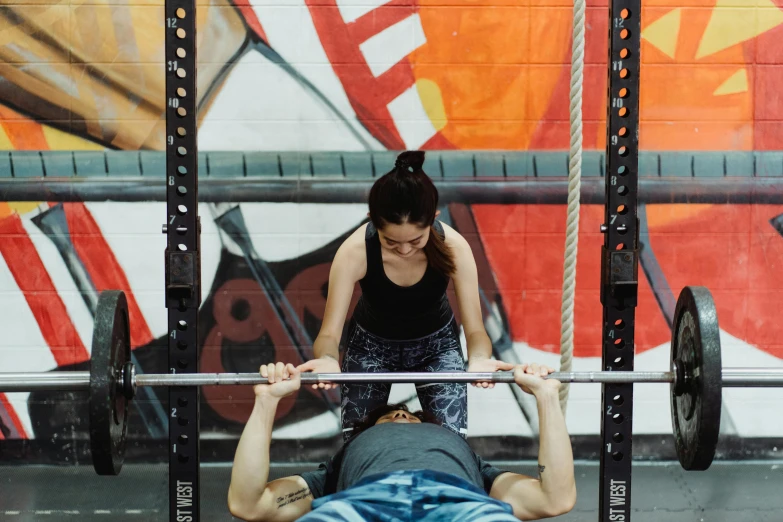 a man lifting a barbell as a woman watches