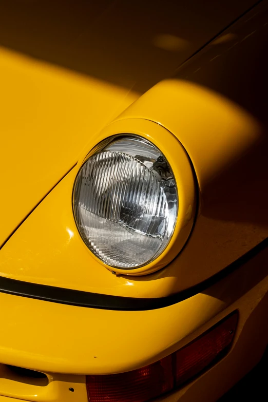 the front end of a bright yellow porsche with its headlights down