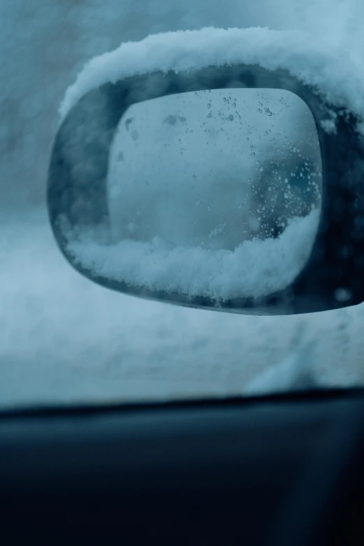 snow is on the window of a car as seen in a side view mirror