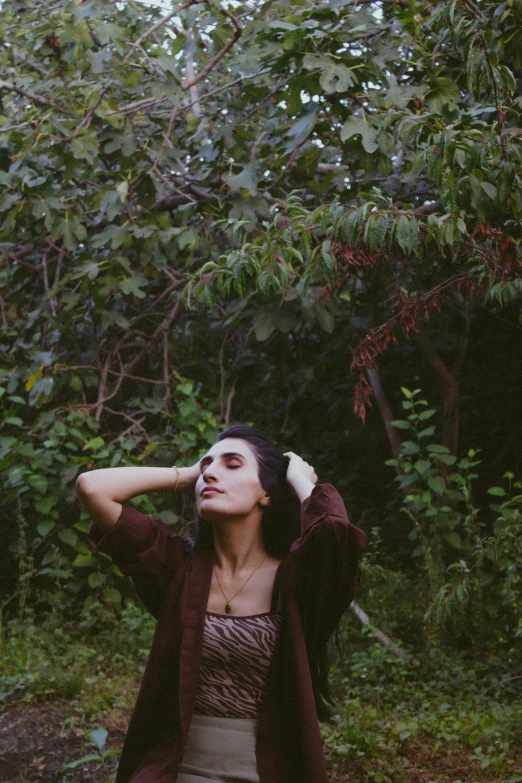 a woman standing in a forest wearing a skirt and jacket