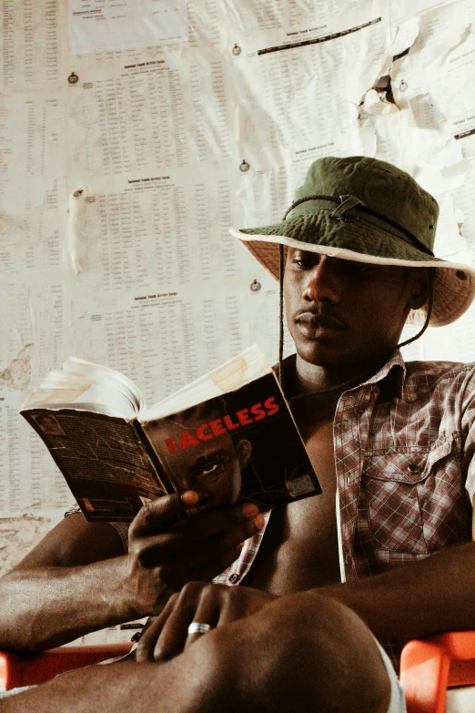 a man reading a book wearing a hat