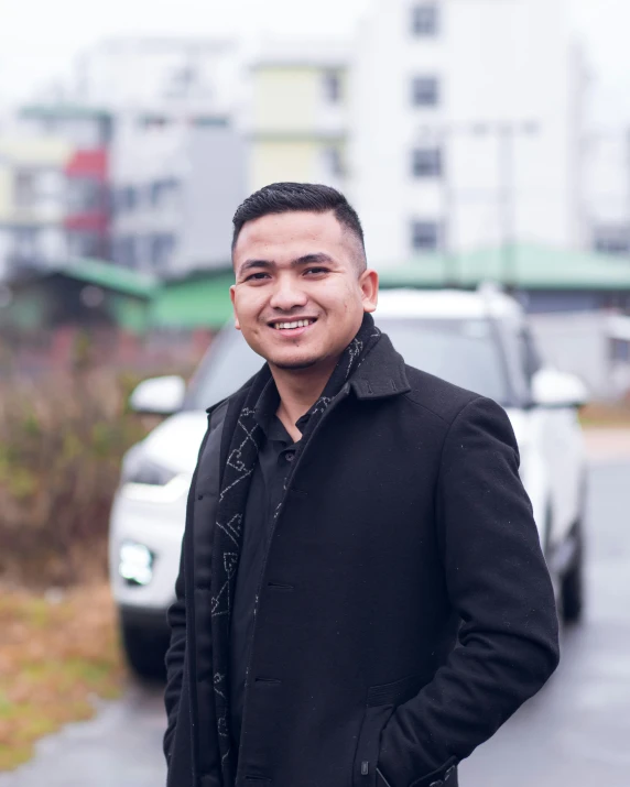 an asian man in front of his car on a wet road