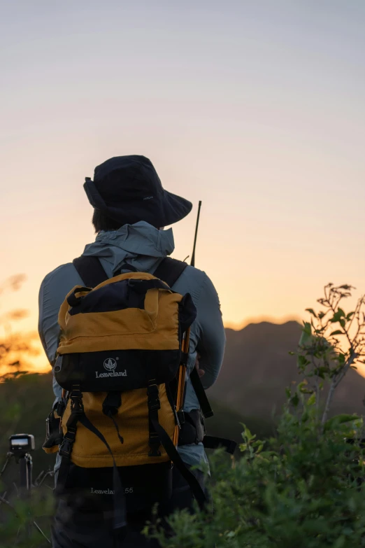 man in hat holding a stick standing on the side of a hill