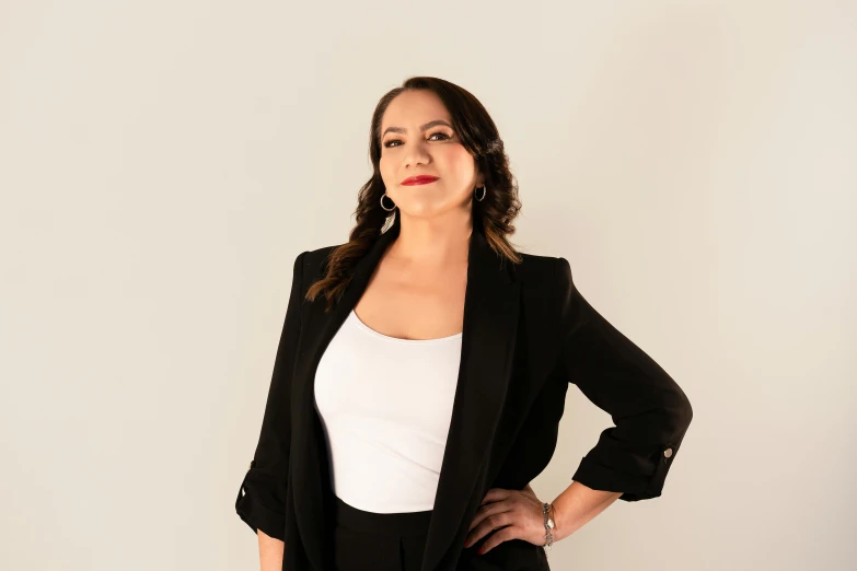 a woman wearing a black blazer and white tank top