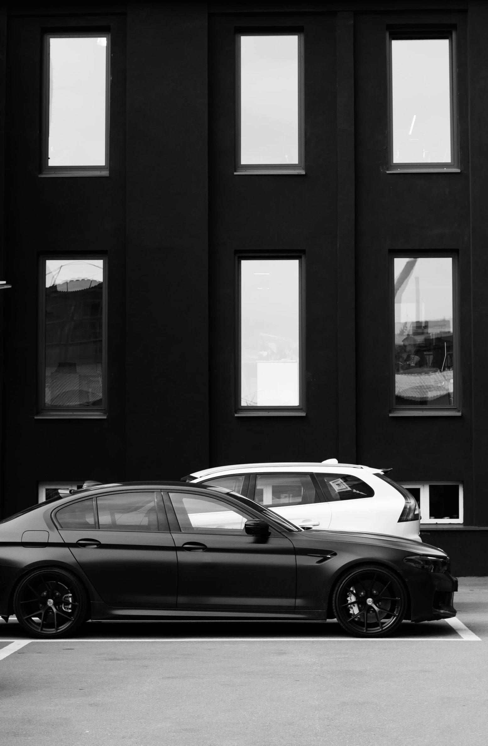 there is a black and white po of a car in front of windows