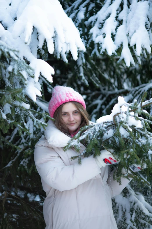 a smiling woman in white coat holding a tree