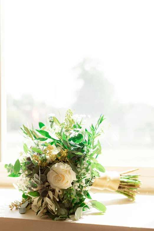 a bouquet of white and green flowers is sitting on the window sill