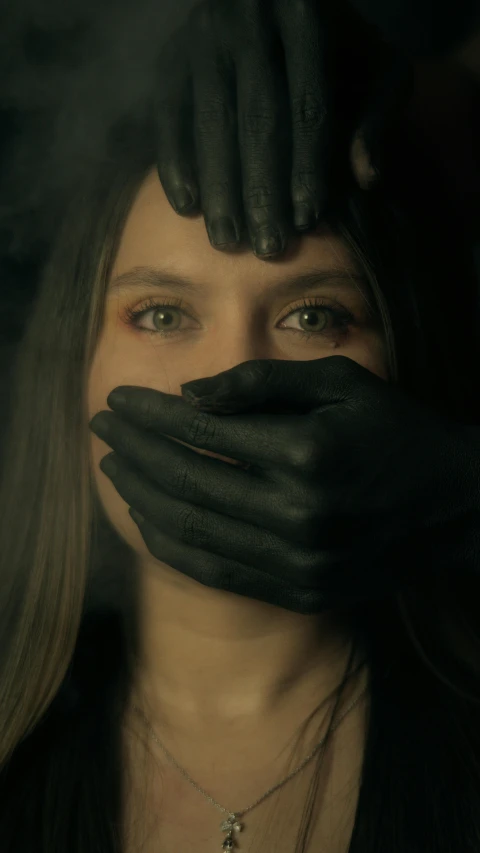 a woman covered with hands and black gloves covering her face