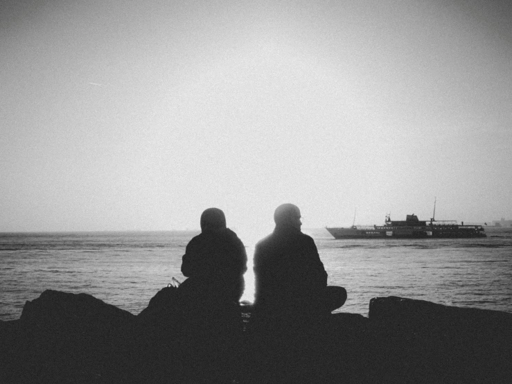 two people are sitting looking out at the water