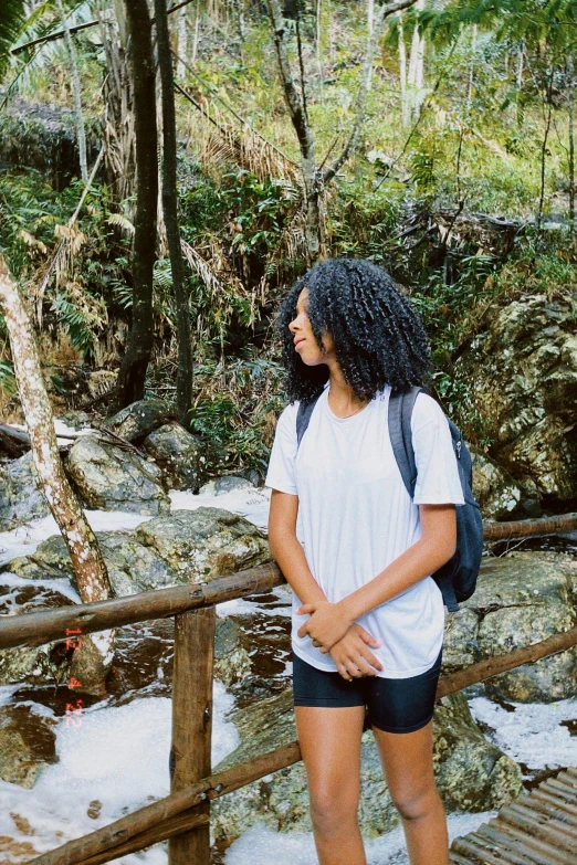 woman standing at a small bridge over a mountain stream