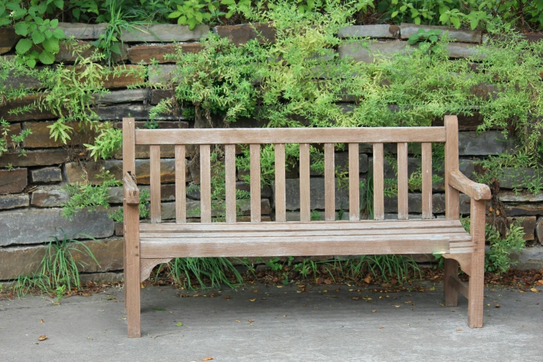 a bench sits in front of a rock wall