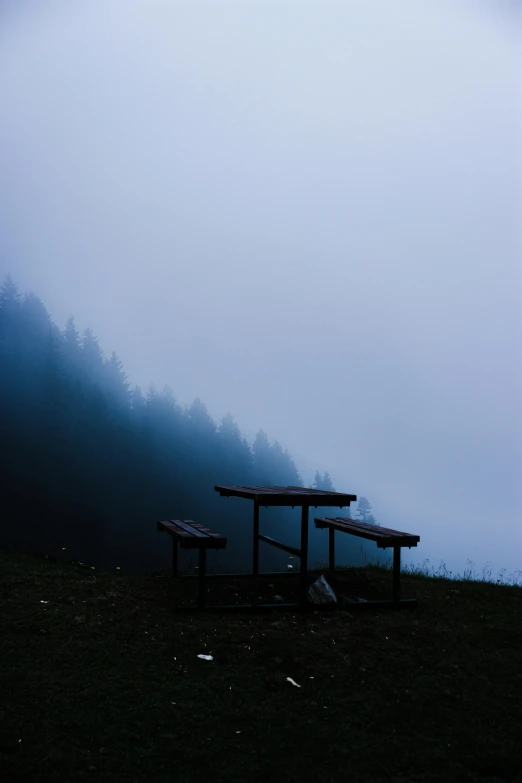 an empty picnic table in the foggy forest