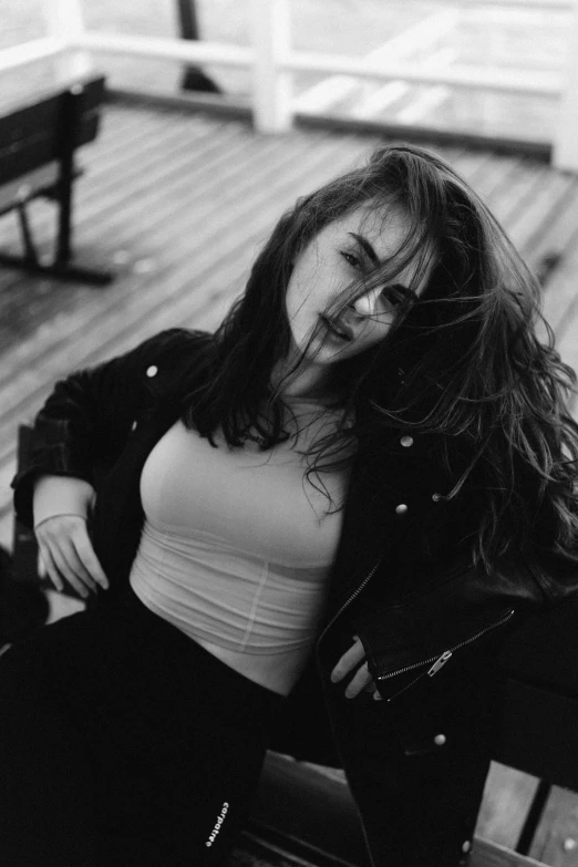 a young woman sitting on top of a wooden bench