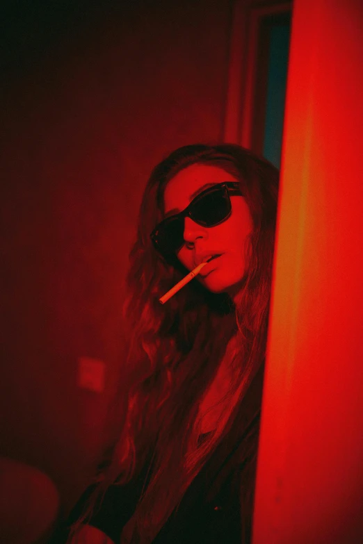 a young woman in sunglasses smoking and looking out the window