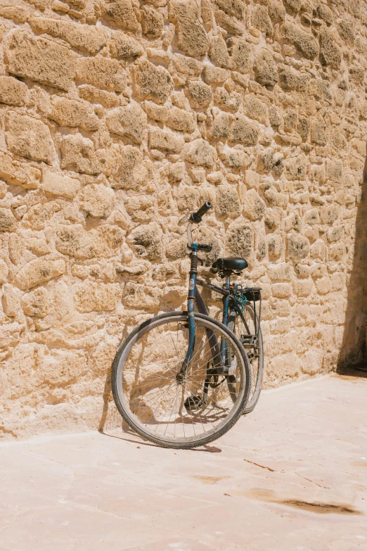 a bike leaning against a rock wall with a black spokes on it