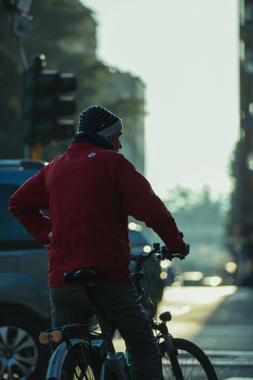 a man in red jacket on a bicycle at street corner