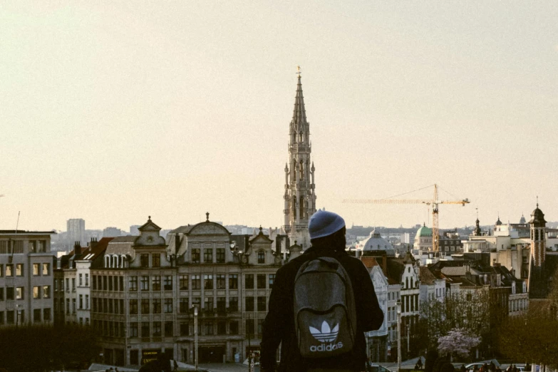 a man in black jacket looking at the city from a bridge