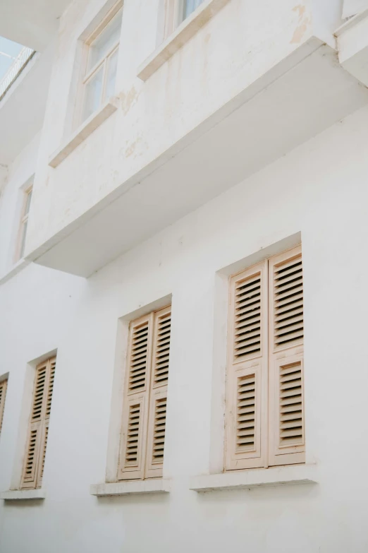 three open shutters on a window of a white building