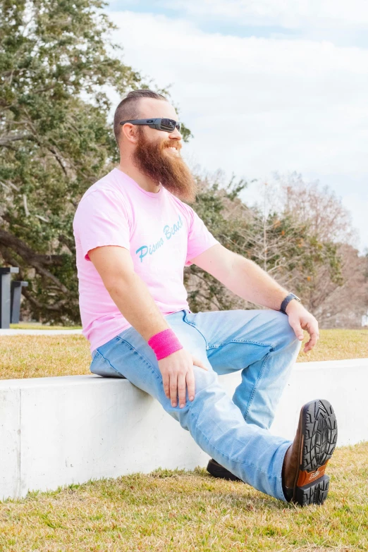 a man with a red beard sitting on a cement wall