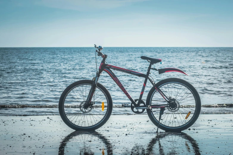 the bike is on a sandy beach with the ocean in the background