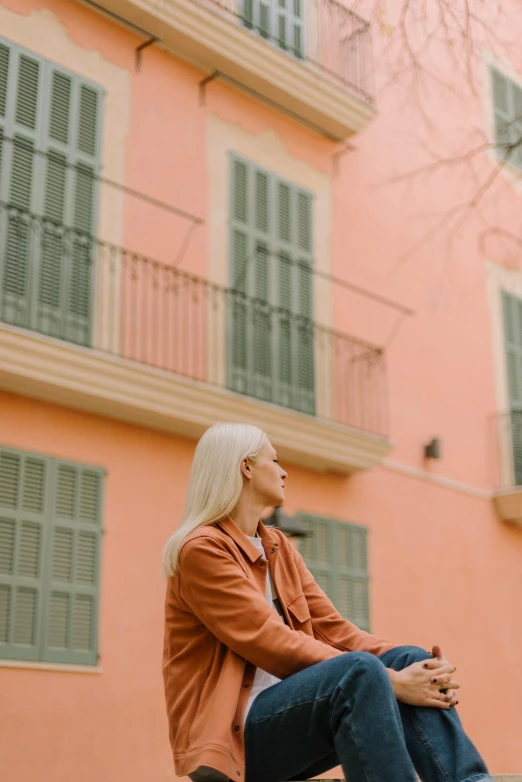 a woman sitting on top of a cement bench near a building