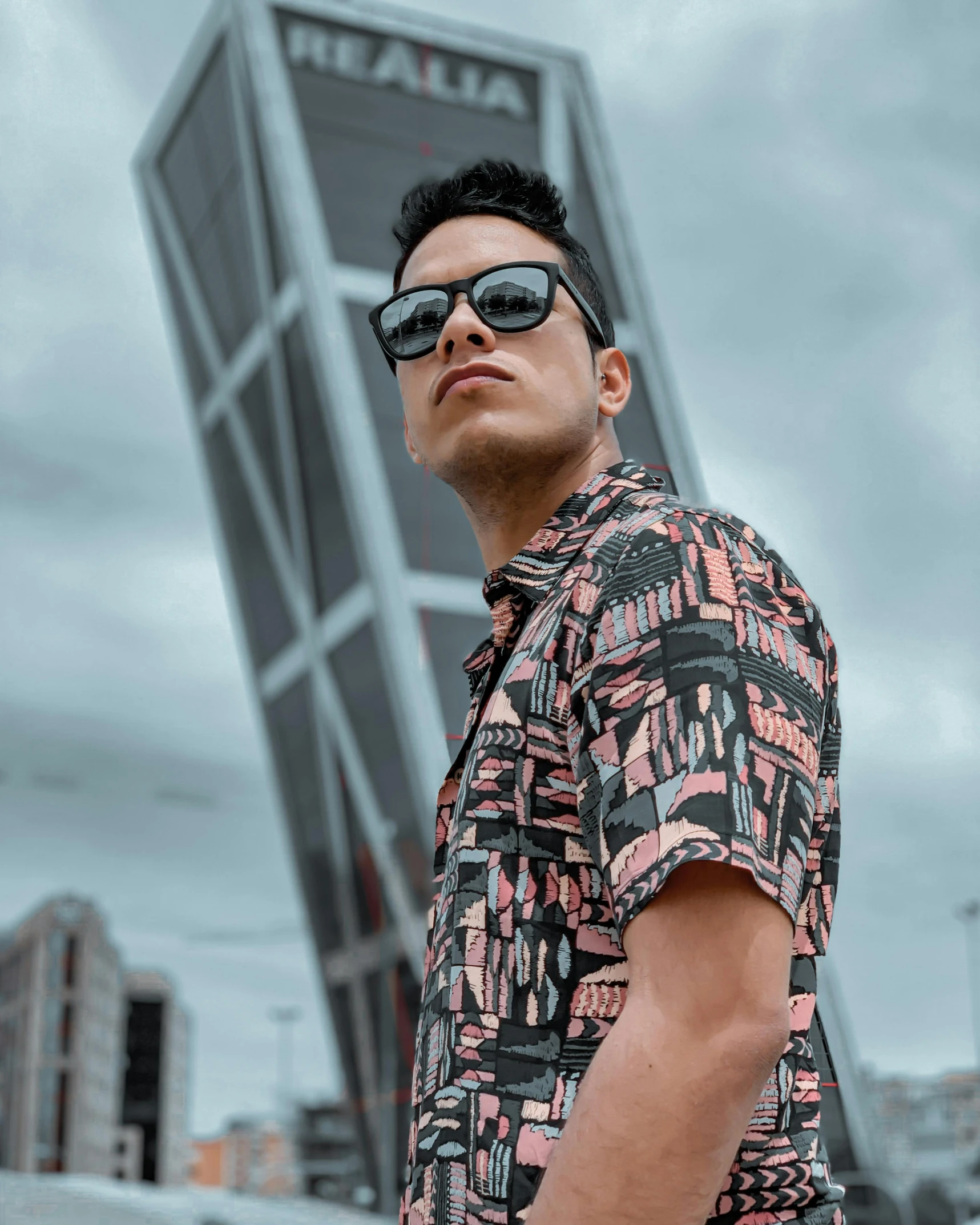 a man wearing sunglasses standing in front of a tall building