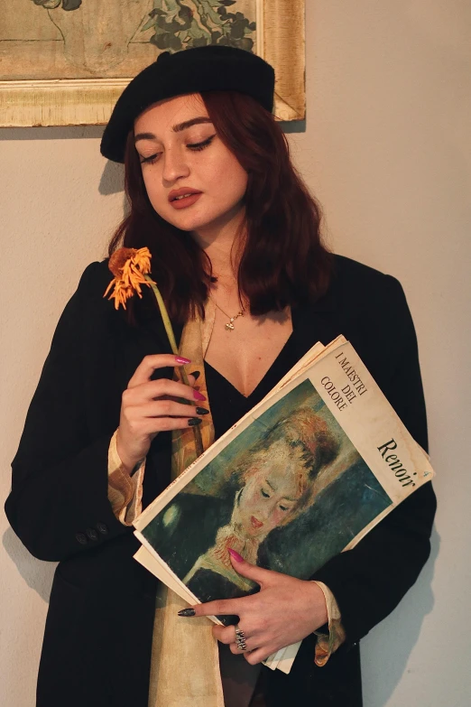the woman is holding a book next to a flower