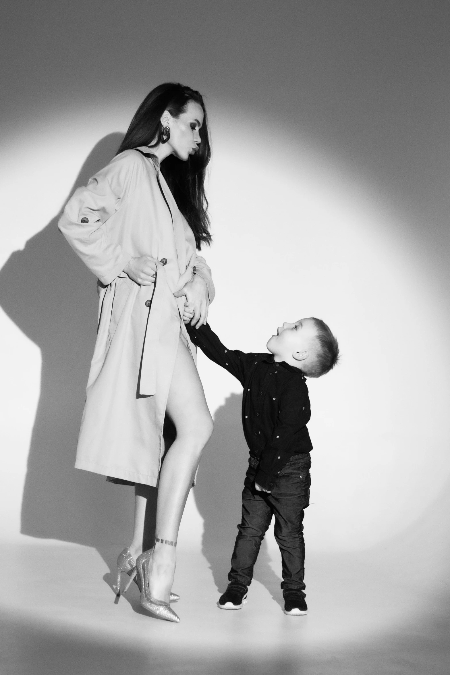 a woman standing next to a boy while holding a hand