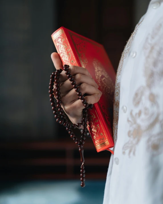 a close up of a woman wearing a rosary and a red box