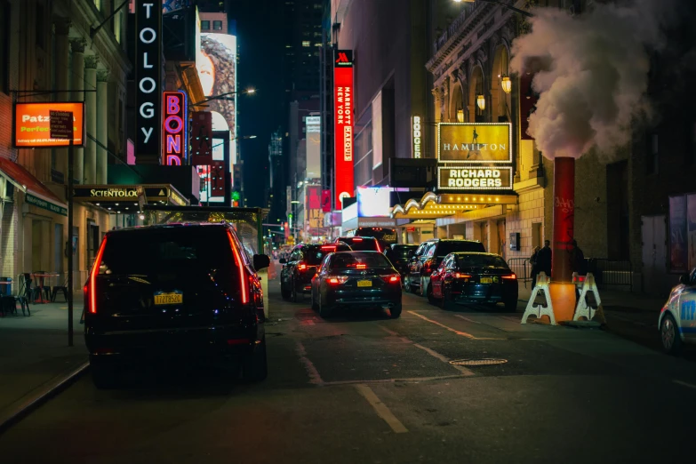 several cars drive down a city street in the evening