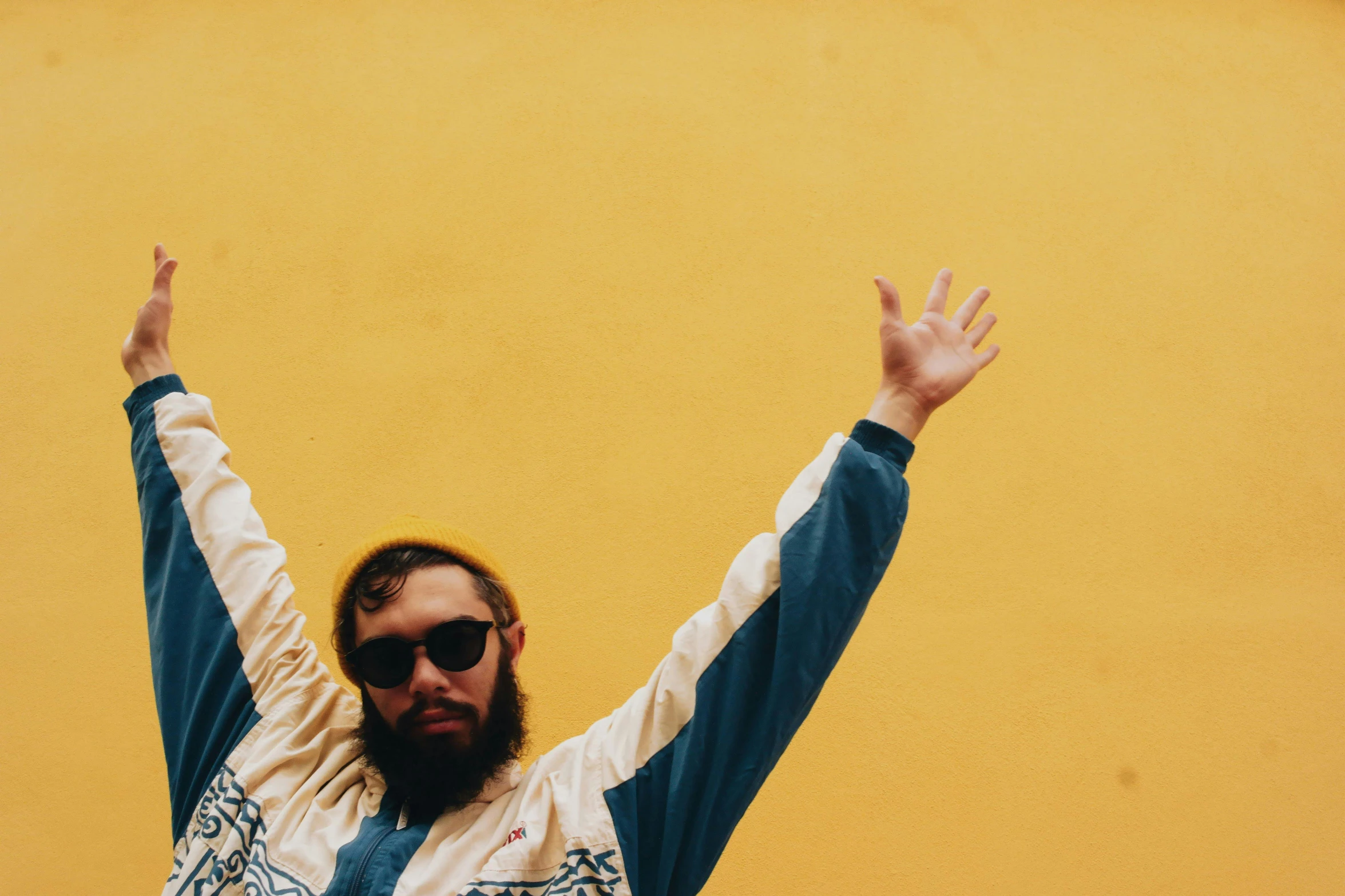 a man with a beard and sunglasses is raising his arms