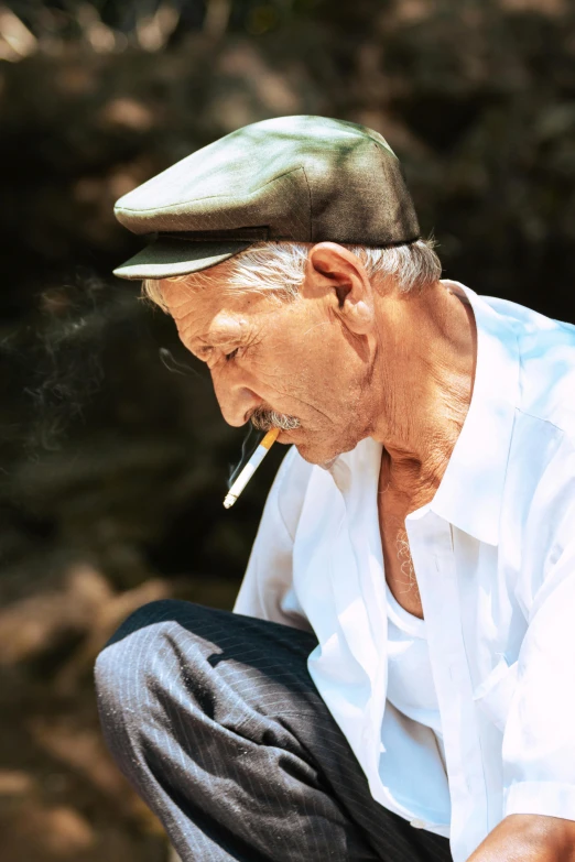 an old man sits on the ground and smokes a cigarette