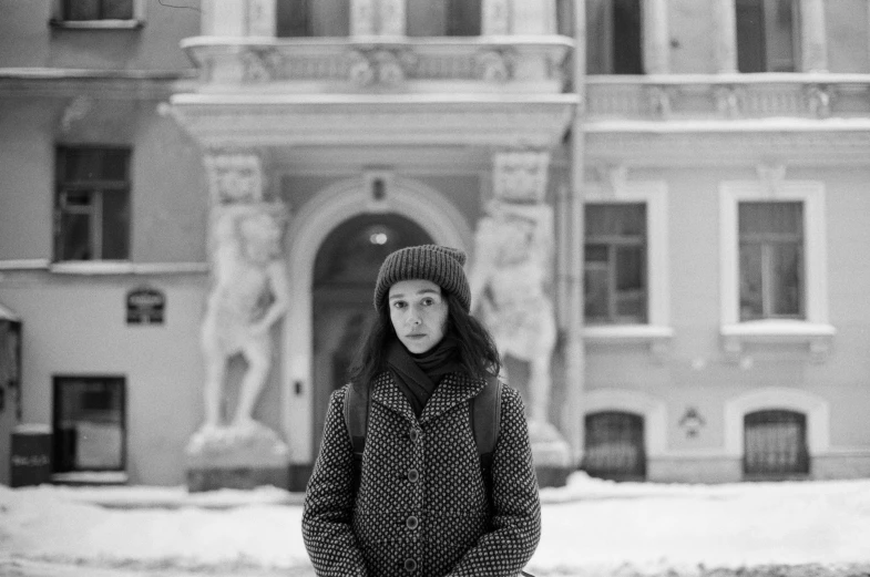 a girl is standing on the street next to an old building